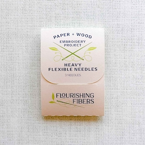 May include: A pink and white package of heavy flexible needles for embroidery projects. The package says "Paper + Wood Embroidery Project Heavy Flexible Needles 3 Needles" and "Flourishing Fibers".