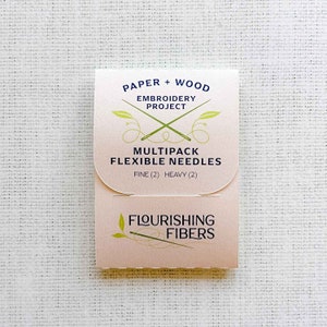 May include: A pink and white package of embroidery needles labeled "Paper + Wood Embroidery Project Multipack Flexible Needles Fine (2) Heavy (2) Flourishing Fibers".