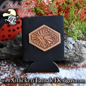 Könnte beinhalten: Schwarzer Getränkekühler mit einem braunen Kunstleder-Blumenmuster. Das Kunstleder ist in Rautenform auf den Kühler genäht. Der Kühler trägt den Text "Chicken Tamale Designs" oben und unten.