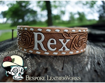 Puede incluir: Un collar de perro de cuero marrón con costuras blancas y un diseño floral. El collar está personalizado con el nombre "Rex" en letras blancas.