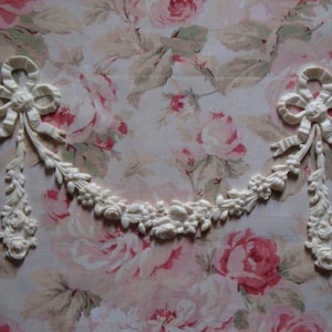 May include: White decorative trim with a floral design and two bows. The trim is made of a lightweight material and has a delicate, feminine look.