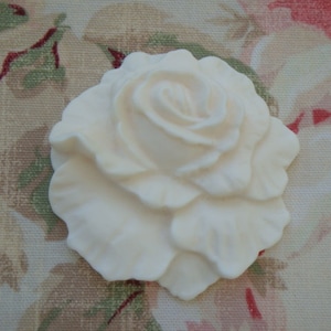 May include: A white, ceramic rose with a detailed, realistic design. The rose is a single bloom with multiple layers of petals.