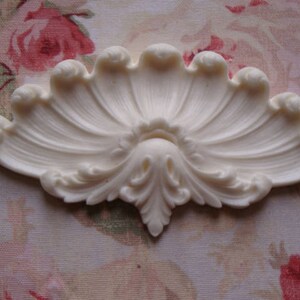 May include: A white, decorative, fan-shaped molding with intricate details. The molding is made of a lightweight material and has a smooth, matte finish.