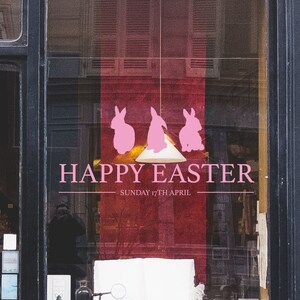 Könnte beinhalten: Schaufenster mit schwarzem Rahmen und der Nummer 10 darüber. Das Fenster zeigt eine rosa Ostergrafik mit drei Hasensilhouetten und den Worten "Happy Easter" und "Sunday 17th April".