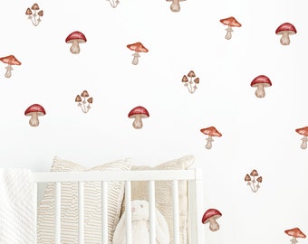 May include: Watercolor mushroom wall decals in shades of red, brown, and tan are scattered across a white wall. A white crib with a striped pillow, a white blanket, and a stuffed bunny are in the foreground.