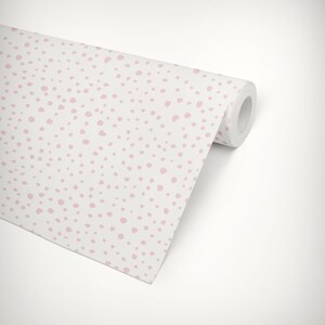 May include: A roll of white wallpaper with a pink polka dot pattern. The wallpaper is rolled up and the end of the roll is visible.