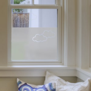 May include: A white window with a frosted glass pane featuring a design of clouds. The window is framed in white and is set in a white wall. A white cushion is on a window seat below the window.