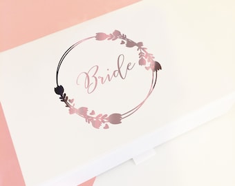 May include: White gift box with a rose gold floral wreath and the word "Bride" in the centre.