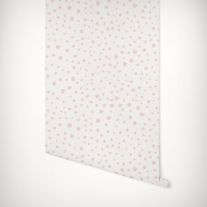 May include: Pink polka dot wallpaper with a white background. The wallpaper is rolled up and ready to be hung.