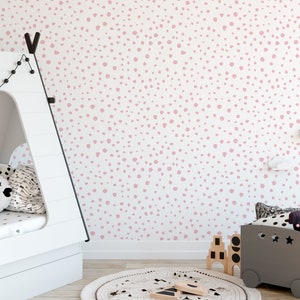 May include: A white wall with a pink polka dot pattern. The wall is in a room with a white teepee bed, a gray toy bin, and a round rug.