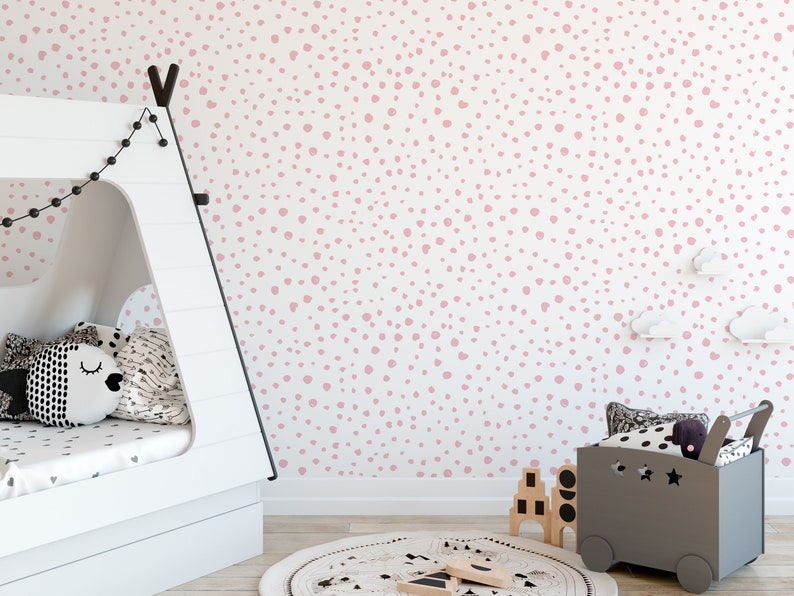 May include: A white wall with a pink polka dot pattern. The wall is in a room with a white teepee bed, a gray toy bin, and a round rug.