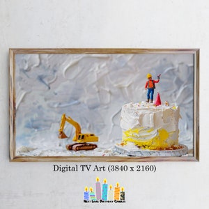May include: A yellow toy excavator sits next to a white and yellow birthday cake with a miniature construction worker on top. The cake is decorated with sprinkles and a red party hat.