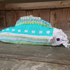 Może przedstawiać: Pluszowa zabawka w kształcie ryby, wykonana na drutach, z niebiesko-zielono-białym paskowanym ciałem i szarą głową z fioletowym okiem. Ryba ma długi, cienki ogon i małe usta.