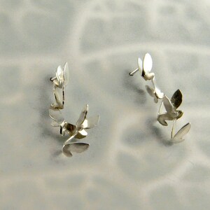 May include: A pair of silver earrings with a delicate floral design. Each earring features multiple small, interconnected flower shapes.