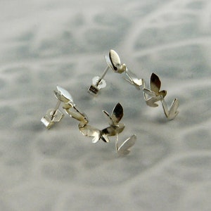 May include: A pair of silver earrings with a leaf design. Each earring has three leaves connected together.