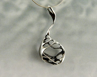Può includere: Una collana con un ciondolo in argento dal design astratto unico. Il ciondolo ha la forma di una lacrima con un motivo traforato.