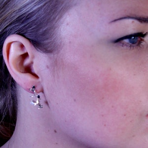 May include: Silver earrings with a delicate leaf design. The earrings are small and dainty, and they would be a great addition to any jewelry collection.
