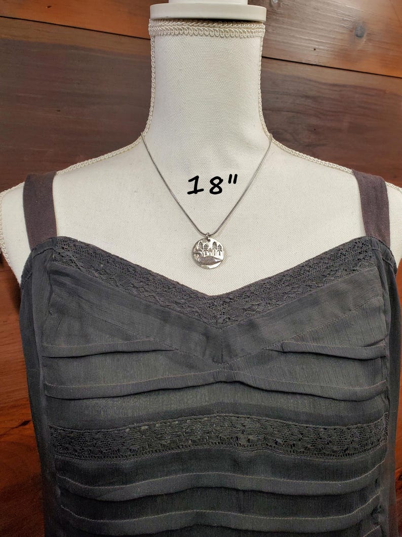 May include: A silver necklace with a round pendant featuring a tree design. The necklace is 18 inches long.