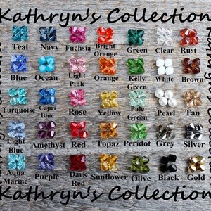 May include: A wooden background displays a color chart from Kathryn's Collection. The chart features various colored beads, including teal, navy, fuchsia, bright orange, green, clear, rust, blue, ocean, light pink, orange, kelly green, white, brown, turquoise, capri blue, rose, yellow, pale green, pearl, tan, light blue, amethyst red, topaz, peridot, grey, silver, aqua marine, purple, dark red, sunflower, olive, black, and gold.