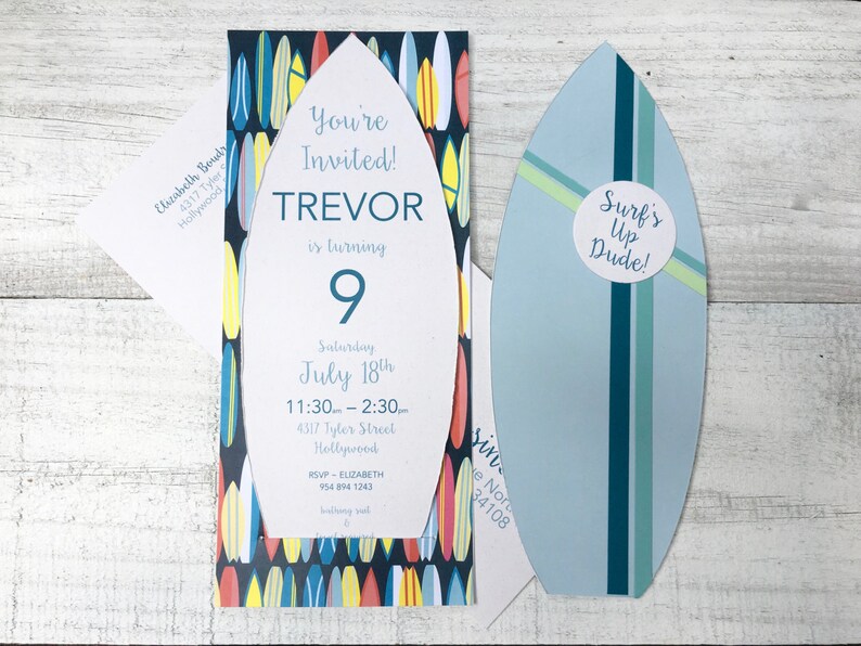 Op de afbeelding: Een blauwe en witte uitnodiging in de vorm van een surfboard met een kleurrijk surfboard-patroon. De uitnodiging zegt "You're Invited! Trevor is turning 9" en bevat details voor een verjaardagsfeest. Een kleinere kaart in de vorm van een surfboard zegt "Surf's Up Dude!"