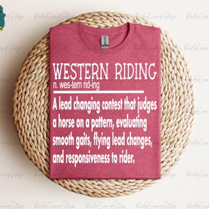 May include: A maroon t-shirt with white text that reads "WESTERN RIDING n. wes-tern rid-ing A lead changing contest that judges a horse on a pattern, evaluating smooth gaits, flying lead changes, and responsiveness to rider."