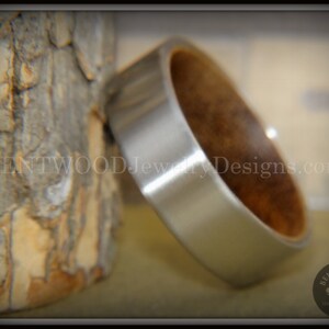 Puede incluir: Un anillo de plata y madera con acabado plateado cepillado. El anillo está hecho de acero inoxidable y madera.