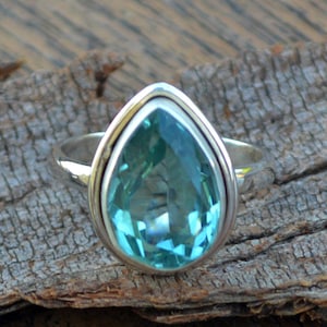 Puede incluir: Un anillo de plata con una piedra preciosa azul en forma de lágrima.