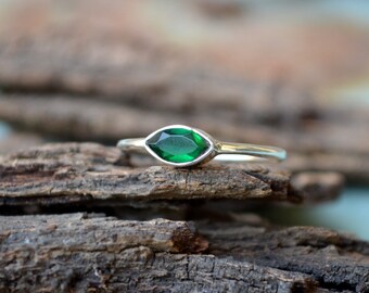 May include: A silver ring with a marquise-shaped green gemstone.