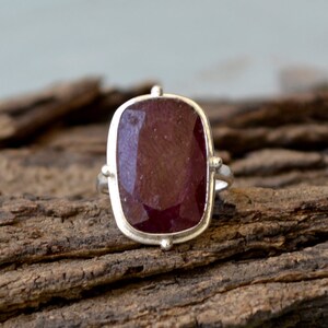 Puede incluir: Un anillo de plata con una gran piedra preciosa rectangular roja engastada en un engaste de bisel.