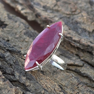 Könnte beinhalten: Ein silberner Ring mit einem großen, facettierten, marquiseförmigen Rubin. Der Rubin hat eine tiefrote Farbe.