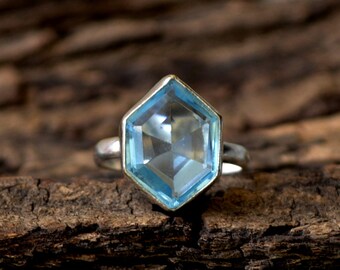 May include: A silver ring with a hexagonal blue topaz gemstone.