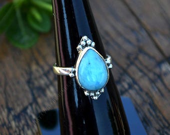 May include: A silver ring featuring a teardrop-shaped blue gemstone set in a silver bezel. The ring is embellished with small silver beads around the gemstone and the band.
