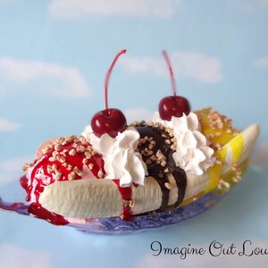 May include: A banana split sundae with three scoops of ice cream, topped with whipped cream, chocolate sauce, cherries, and chopped nuts. The sundae is served in a banana boat.