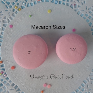May include: Two pink macarons on a white doily with colorful sprinkles. The macarons are 2 inches and 1.5 inches in diameter. The text "Imagine Out Loud" is written below the macarons.