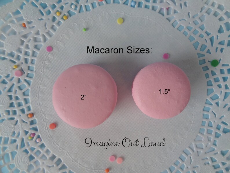 May include: Two pink macarons on a white doily with colorful sprinkles. The macarons are 2 inches and 1.5 inches in diameter. The text "Imagine Out Loud" is written below the macarons.