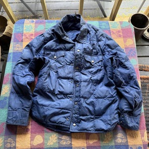 May include: A navy blue quilted shirt jacket with a button-up front and two chest pockets.