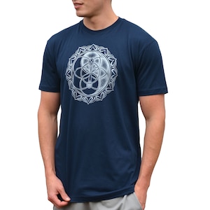May include: A navy blue t-shirt with a white graphic of a yin yang symbol with a flower of life design inside. The graphic is surrounded by a circle of stylized flower petals.