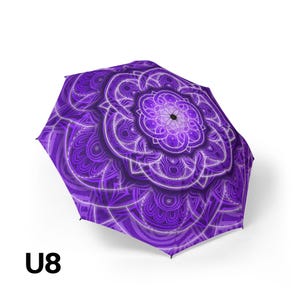 May include: A purple umbrella featuring a symmetrical, intricate mandala pattern in various shades of violet and white. The design radiates from a central point, creating a complex, layered floral-like geometric motif across the canopy. The text U8 is visible.