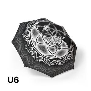 May include: A black and white umbrella featuring a detailed stippled mandala design with geometric circular patterns and a repeating heart-shaped border. The text U6 is printed in black in the lower left corner of the image.