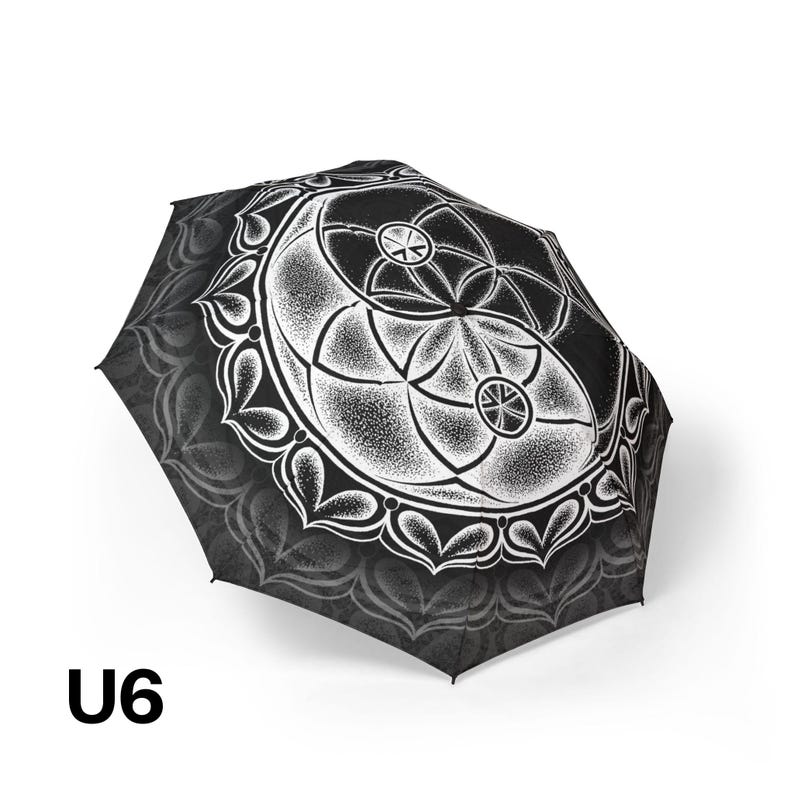 May include: A black and white umbrella featuring a detailed stippled mandala design with geometric circular patterns and a repeating heart-shaped border. The text U6 is printed in black in the lower left corner of the image.