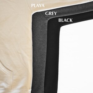 May include: Close-up of three hoodies in Playa, Grey, and Black. The Playa hoodie is a light beige color, the Grey hoodie is a medium gray, and the Black hoodie is a solid black. The names of the colors are printed on the image.