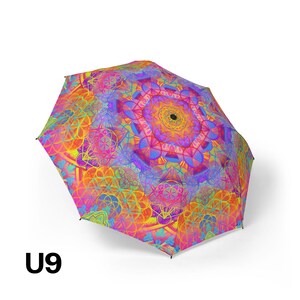 May include: A collapsible umbrella featuring a vibrant, multi-colored geometric pattern with overlapping circular mandala designs in shades of hot pink, orange, yellow, and blue. The canopy displays a repeating sacred geometry motif and the text U9.