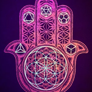 May include: A neon pink and purple Hamsa hand design with geometric shapes and patterns. The hand features a central mandala-like design with a flower of life pattern. The background is a dark purple.