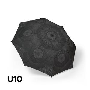 May include: A black umbrella featuring a dark gray repeating mandala pattern across the canopy. The umbrella is shown in an open position, displaying the intricate circular geometric designs. The text U10 is printed in black in the bottom left corner.
