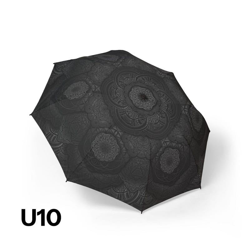 May include: A black umbrella featuring a dark gray repeating mandala pattern across the canopy. The umbrella is shown in an open position, displaying the intricate circular geometric designs. The text U10 is printed in black in the bottom left corner.