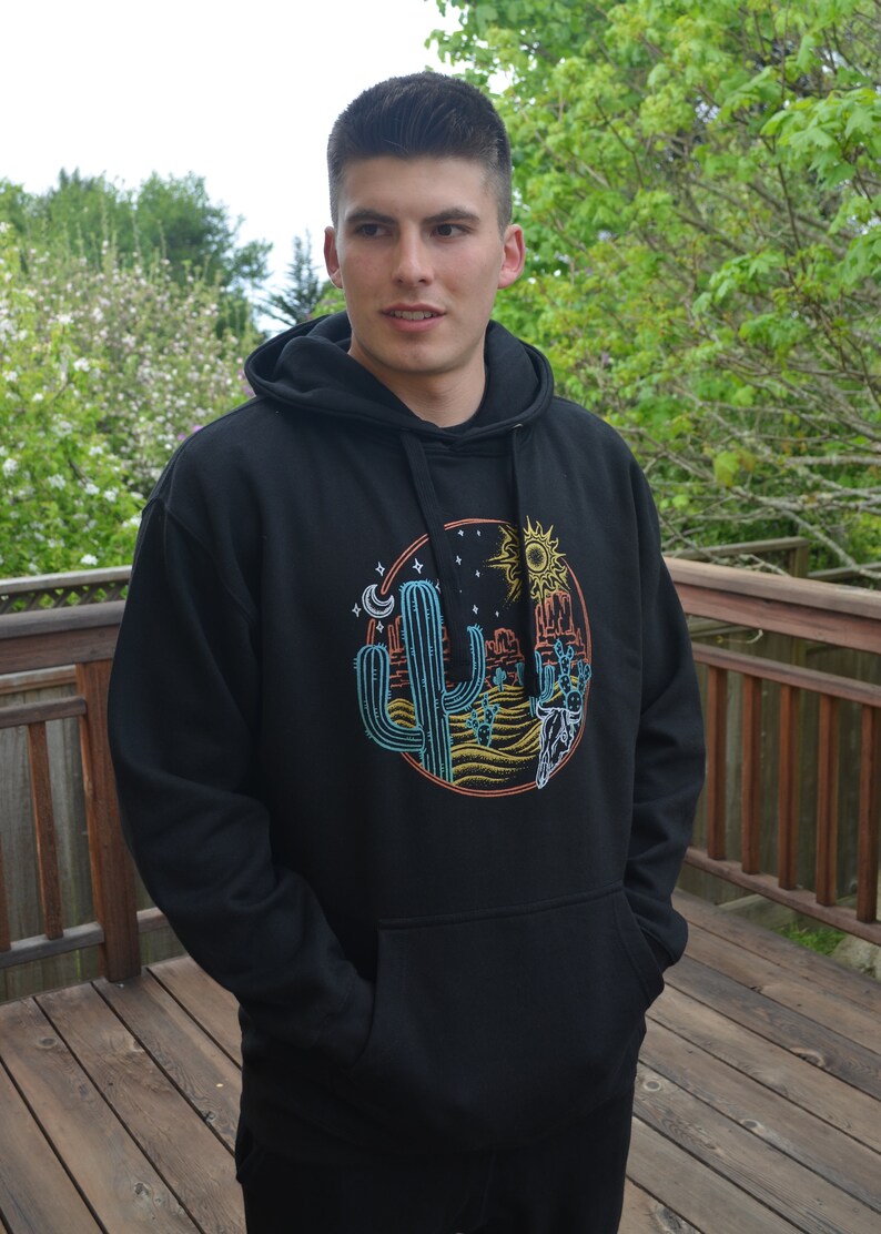 May include: Black hooded sweatshirt with a graphic print of a desert scene with a cactus, mountains, a sun, and a moon.