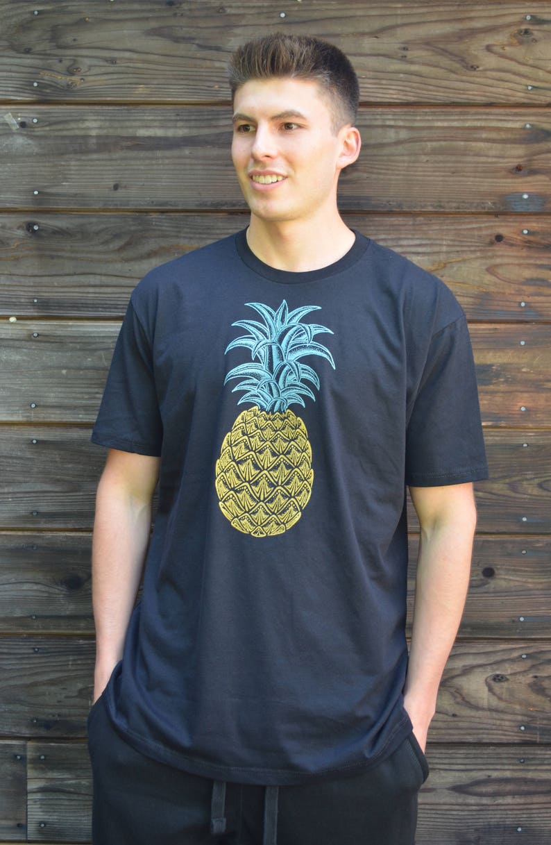 May include: A black t-shirt with a yellow pineapple graphic. The pineapple has blue leaves and a yellow body.
