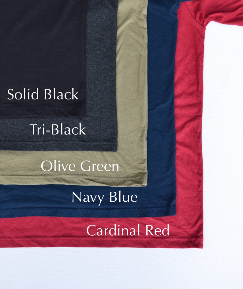 May include: Five different colored t-shirts stacked on top of each other. The colors are solid black, tri-black, olive green, navy blue, and cardinal red. The t-shirts are all the same style and size.