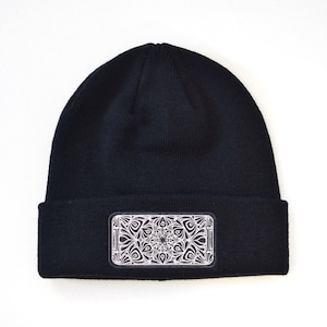 May include: Black beanie with a white mandala design patch on the front.
