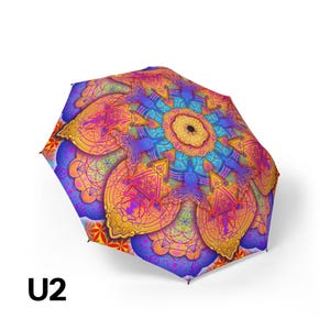 May include: A collapsible umbrella featuring a vibrant, multi-colored mandala pattern with intricate geometric shapes, triangles, and circular motifs in shades of orange, yellow, purple, and blue. The text U2 is printed in black in the corner.